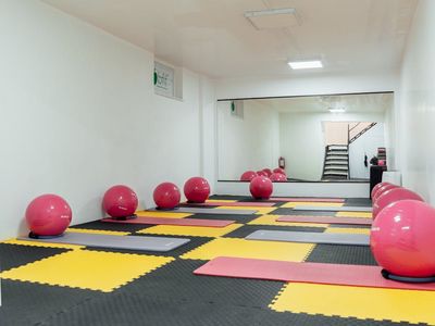 Bright gym interior with large windows and mats.